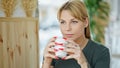 Young blonde woman drinking coffee sitting on table at coffee shop Royalty Free Stock Photo