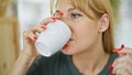 Young blonde woman drinking coffee sitting on table at coffee shop Royalty Free Stock Photo