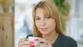 Young blonde woman drinking coffee sitting on table at coffee shop Royalty Free Stock Photo