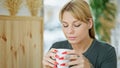 Young blonde woman drinking coffee sitting on table at coffee shop Royalty Free Stock Photo