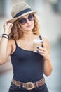 Young blonde woman drinking coffee somewhere in the city streets