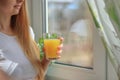 Young blonde woman drinking orange juice and looking at the window Royalty Free Stock Photo