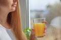 Young blonde woman drinking orange juice and looking at the window Royalty Free Stock Photo