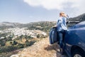 Young blonde woman driving convertible blue rental car without roof on mountain road in Naxos island, Greece Royalty Free Stock Photo