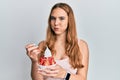 Young blonde woman eating strawberry ice cream puffing cheeks with funny face Royalty Free Stock Photo