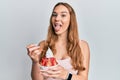 Young blonde woman eating strawberry ice cream sticking tongue out happy with funny expression Royalty Free Stock Photo