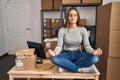 Young blonde woman ecommerce business worker doing yoga sitting on table at office Royalty Free Stock Photo