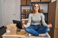 Young blonde woman ecommerce business worker doing yoga sitting on table at office Royalty Free Stock Photo