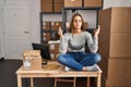 Young blonde woman ecommerce business worker doing yoga sitting on table at office Royalty Free Stock Photo