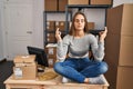 Young blonde woman ecommerce business worker doing yoga sitting on table at office Royalty Free Stock Photo