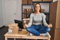 Young blonde woman ecommerce business worker doing yoga sitting on table at office Royalty Free Stock Photo