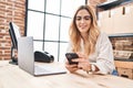 Young blonde woman ecommerce business worker using laptop and smartphone at office Royalty Free Stock Photo
