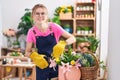 Young blonde woman florist cutting plants smiling at flower shop Royalty Free Stock Photo