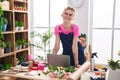 Young blonde woman florist smiling confident using laptop at flower shop Royalty Free Stock Photo