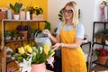 Young blonde woman florist smiling confident watering plant at flower shop Royalty Free Stock Photo