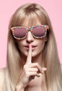 Young blonde woman with fun candy glasses and finger on lips on Royalty Free Stock Photo