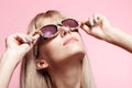 Young blonde woman with fun candy glasses on pink background Royalty Free Stock Photo