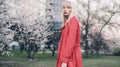 Young blonde woman goes for walk in spring garden on background of blossoming trees. Royalty Free Stock Photo