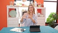 Young blonde woman having online lesson counting fingers at dinning room