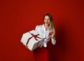 Young blonde woman hold white box gift present smiling try to open it on Birthday party celebration on red Royalty Free Stock Photo