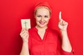 Young blonde woman holding catholic cross reminder surprised with an idea or question pointing finger with happy face, number one