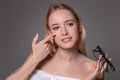 Young blonde woman holding contact lens on finger in front of her face and holding in her other hand a black glasses on Royalty Free Stock Photo