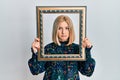 Young blonde woman holding empty frame depressed and worry for distress, crying angry and afraid Royalty Free Stock Photo