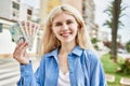 Young blonde woman holding english banknotes pounds, showing money smiling happy and confident outdoors