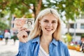 Young blonde woman holding english banknotes pounds, showing money smiling happy and confident outdoors