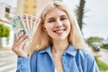 Young blonde woman holding english banknotes pounds, showing money smiling happy and confident outdoors