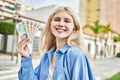 Young blonde woman holding english banknotes pounds, showing money smiling happy and confident outdoors