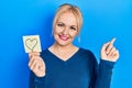 Young blonde woman holding heart reminder smiling happy pointing with hand and finger to the side