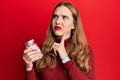 Young blonde woman holding jar of pills serious face thinking about question with hand on chin, thoughtful about confusing idea Royalty Free Stock Photo