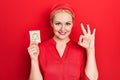 Young blonde woman holding jew star reminder doing ok sign with fingers, smiling friendly gesturing excellent symbol Royalty Free Stock Photo