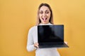 Young blonde woman holding laptop celebrating crazy and amazed for success with open eyes screaming excited Royalty Free Stock Photo