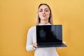 Young blonde woman holding laptop looking at the camera blowing a kiss being lovely and sexy Royalty Free Stock Photo