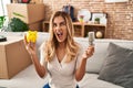 Young blonde woman holding led bulb and piggy bank angry and mad screaming frustrated and furious, shouting with anger looking up Royalty Free Stock Photo