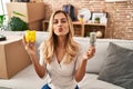 Young blonde woman holding led bulb and piggy bank looking at the camera blowing a kiss being lovely and sexy Royalty Free Stock Photo