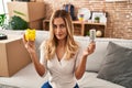 Young blonde woman holding led bulb and piggy bank relaxed with serious expression on face Royalty Free Stock Photo