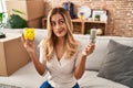Young blonde woman holding led bulb and piggy bank smiling looking to the side and staring away thinking Royalty Free Stock Photo