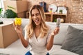 Young blonde woman holding led bulb and piggy bank winking looking at the camera with sexy expression, cheerful and happy face Royalty Free Stock Photo