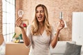 Young blonde woman holding led lightbulb and incandescent bulb winking looking at the camera with sexy expression, cheerful and Royalty Free Stock Photo