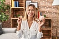 Young blonde woman holding piggy bank and bitcoin smiling with a happy and cool smile on face