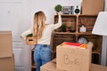 Young blonde woman holding plant standing on back view at new home Royalty Free Stock Photo