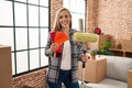 Young blonde woman holding roller painter and paint samples at new home smiling with a happy and cool smile on face Royalty Free Stock Photo