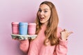 Young blonde woman holding tray with take away coffee pointing thumb up to the side smiling happy with open mouth Royalty Free Stock Photo