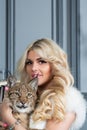 Young blonde woman holds lynx cub on in