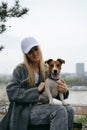 Young blonde woman hugs a dog in a spring park. Female owner with a Jack Russell terrier puppy on a walk, a close-up Royalty Free Stock Photo