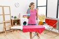 Young blonde woman ironing clothes at home smiling happy pointing with hand and finger to the side Royalty Free Stock Photo