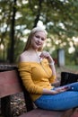 Young blonde woman listening to music on her phone in the park Royalty Free Stock Photo